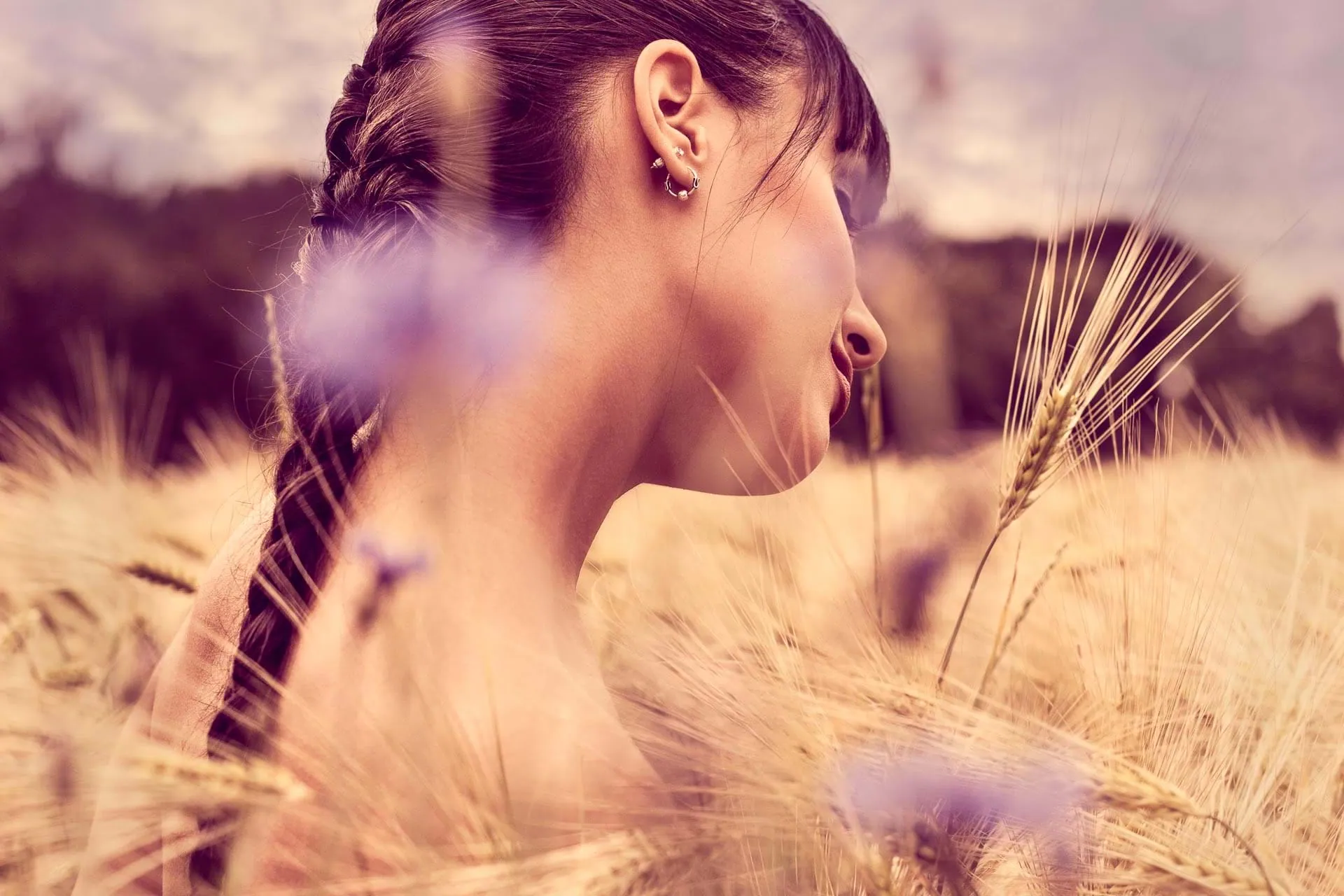 Woman in a wheat field — profile shot with cornflowers in soft late-summer light